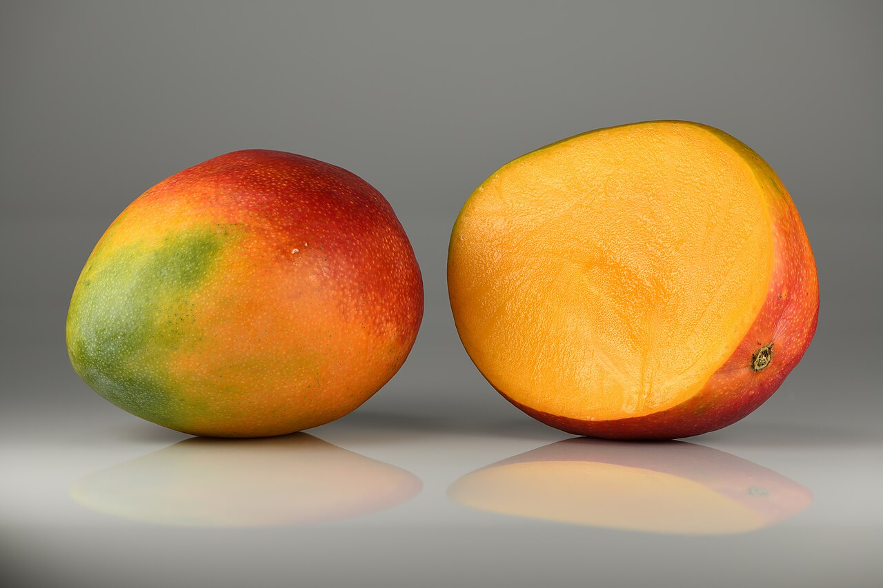 Een mango, heel en gehalveerd.
